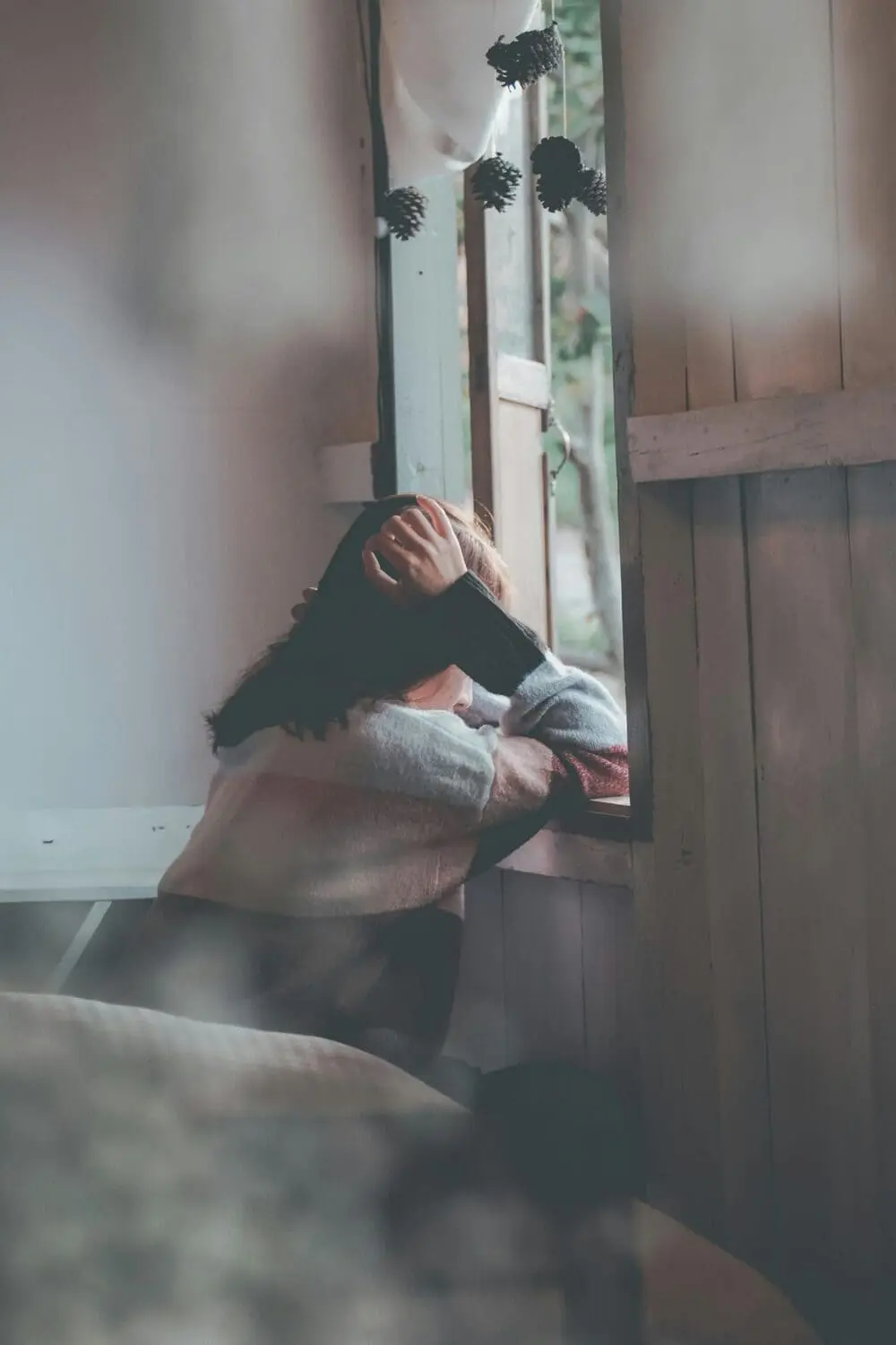 femme à une fenêtre et se tenant la tête 